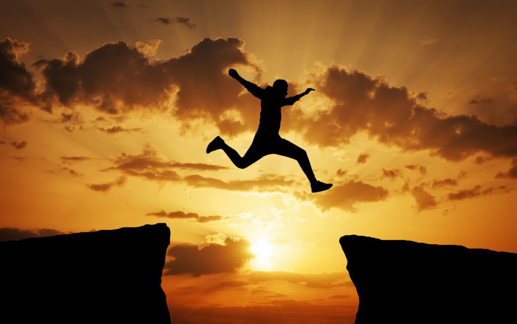 Shadow of a man jumping across the gap from one rock to cling to the other.