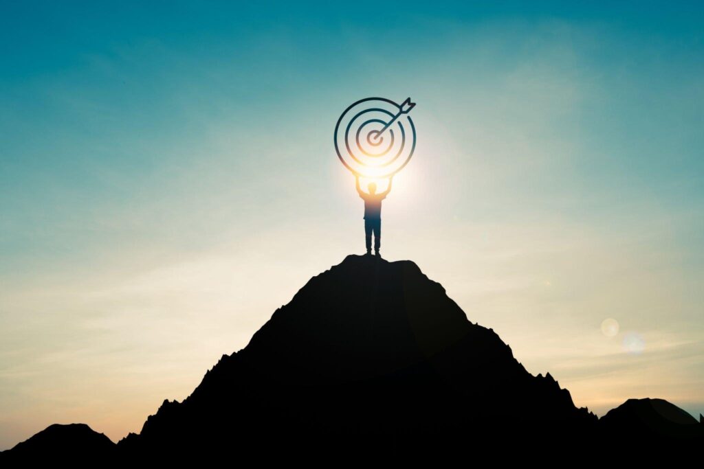 A man on top of the mountain holding a shadowed dart board who achieved success.