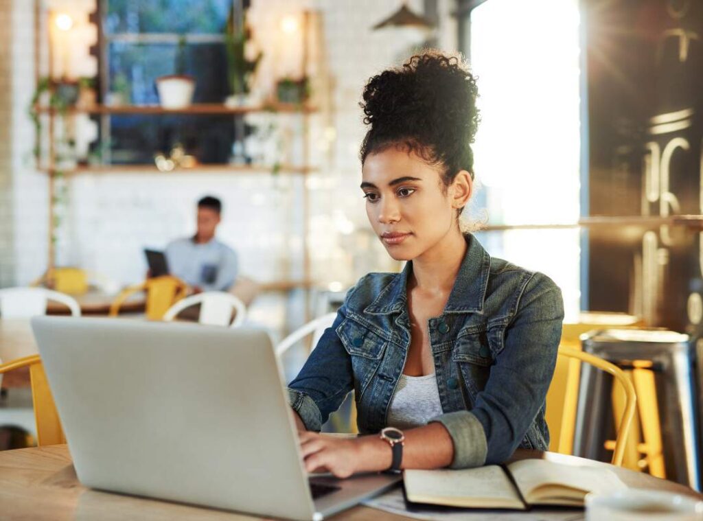 A girl at a coffee shop using a laptop.